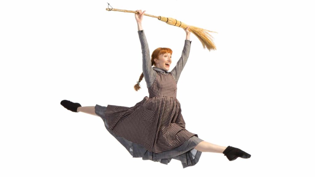 Ballet Dancer dressed as Anne of Green Gables, jumping into the air with broom in hands.