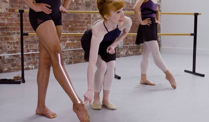 Image of a dancer pointing to another dancers leg